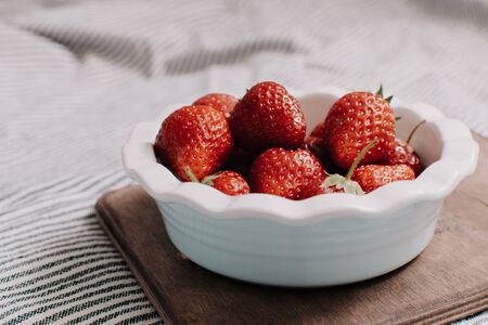 Strawberries in a plate on the wooden board. Summer concept.の写真素材