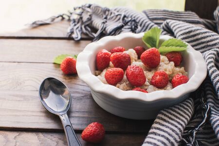 Breakfast. Tasty oatmeal with berries. Healthy breakfast ingredients. Oat granola in bowl with strawberry and mint. Granola for breakfast with berries.の写真素材