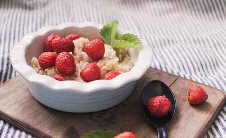 Breakfast. Tasty oatmeal with berries. Healthy breakfast ingredients. Oat granola in bowl with strawberry and mint. Granola for breakfast with berries.の写真素材