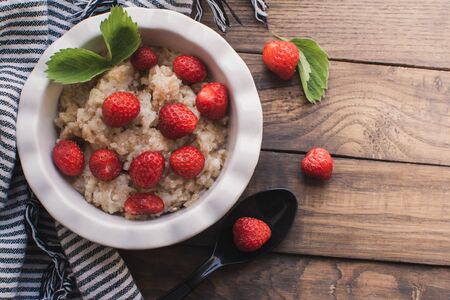 Breakfast. Tasty oatmeal with berries. Healthy breakfast ingredients. Oat granola in bowl with strawberry and mint. Granola for breakfast with berries.の写真素材