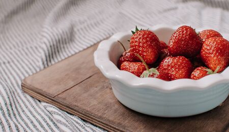 Strawberries in a plate on the wooden board. Summer concept.の写真素材