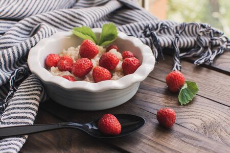 Breakfast. Tasty oatmeal with berries. Healthy breakfast ingredients. Oat granola in bowl with strawberry and mint. Granola for breakfast with berries.の写真素材