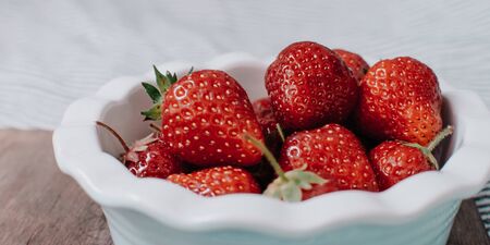 Strawberries in a plate on the wooden board. Summer concept.の写真素材