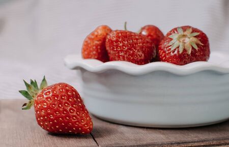 Strawberries in a plate on the wooden board. Summer concept.の写真素材