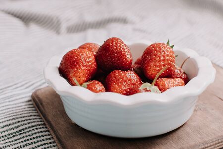 Strawberries in a plate on the wooden board. Summer concept.の写真素材