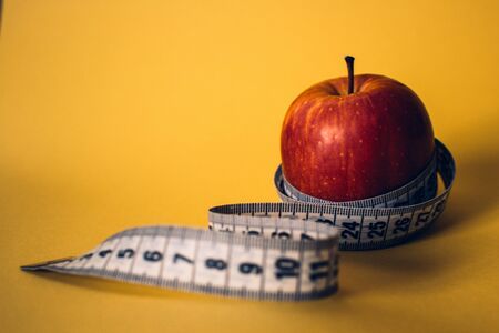 Healthy lifestyle concept. Red apple with measuring tape. Dieting concept.の写真素材