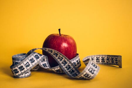 Healthy lifestyle concept. Red apple with measuring tape. Dieting concept.の写真素材