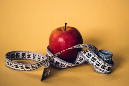 Healthy lifestyle concept. Red apple with measuring tape. Dieting concept.の写真素材