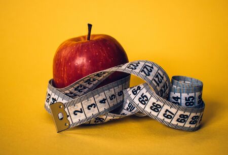 Healthy lifestyle concept. Red apple with measuring tape. Dieting concept.の写真素材