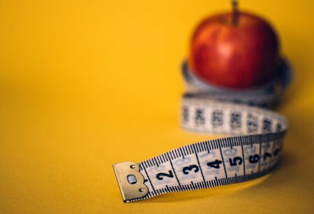 Healthy lifestyle concept. Red apple with measuring tape. Dieting concept.の写真素材
