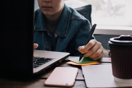 Teenage boy works at desk in his bedroom. School and work concept. Home education. Homework. Home schooling. Working at home. の写真素材