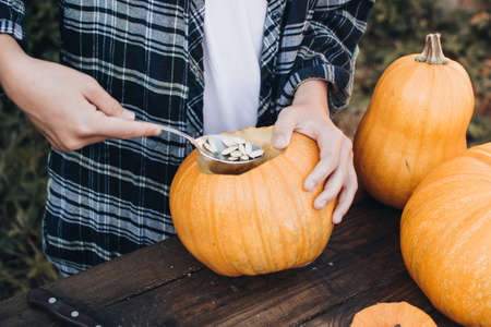 Carving a spooky Jack-o-lantern face on a pumpkin for Halloween. Preparation for holiday. Making decoration for the Halloween party. Cutting pumpkins for the holiday.の写真素材