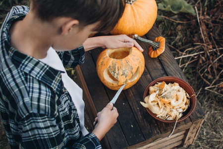 Carving a spooky Jack-o-lantern face on a pumpkin for Halloween. Preparation for holiday. Making decoration for the Halloween party. Cutting pumpkins for the holiday.の写真素材