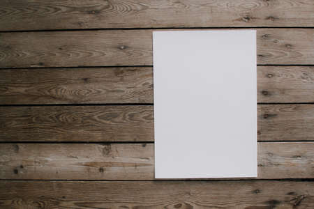 Blank sheet of paper on vintage wooden table background. White paper with plenty of copy space. Blank paperwork template for design portfolios. Top view.の写真素材