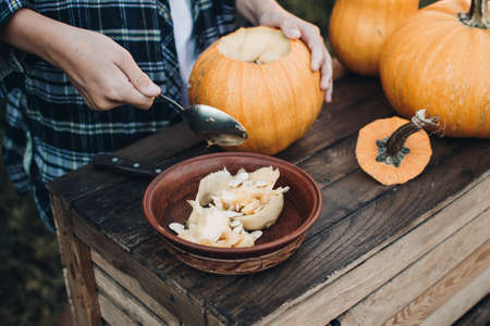 Carving a spooky Jack-o-lantern face on a pumpkin for Halloween. Preparation for holiday. Making decoration for the Halloween party. Cutting pumpkins for the holiday.の写真素材