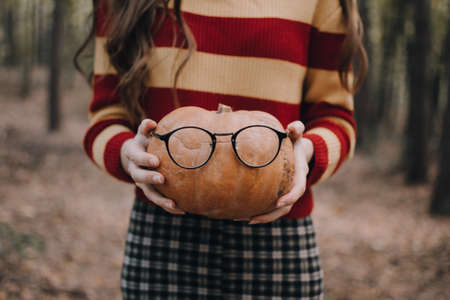 The girl in the forest with a pumpkin. Halloween holidays and Thanksgiving concept. Autumn mood.の写真素材