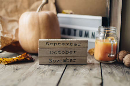 Wooden blocks against a rustic wood background with pumpkins and autumn leaves. Background with candle and pumpkin. Autumn background. Autumn months.の写真素材
