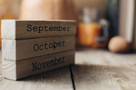 Wooden blocks against a rustic wood background with pumpkins and autumn leaves. Background with candle and pumpkin. Autumn background. Autumn months.の写真素材