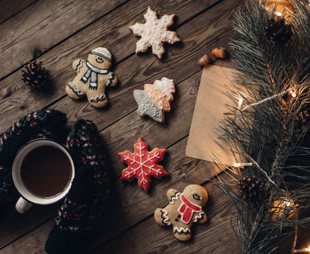 Hands in mittens. Christmas cookies. Christmas background and decoration on dark wooden board. Christmas mood. Flat lay winter cozy vintage background.の写真素材