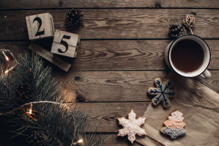 Wooden blocks against a rustic wood background with Christmas tree, cookies, cup of tea or coffee and lights. Background with christmas decor. Christmas background. Winter months.の写真素材
