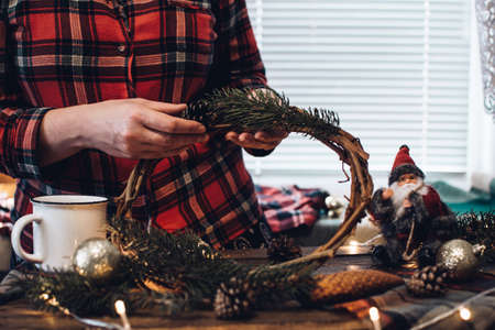 Making of Christmas wreath from nature materials on a dark wooden table. Scandinavian hygge styled Christmas composition. Cozy winter homely scene with decorations.の写真素材