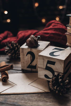 Wooden calendar blocks. Scandinavian hygge styled Christmas composition. Cozy winter homely scene with books, cinnamon sticks and knitted things. Santa Claus working place. Flatlay. Home decor.の写真素材