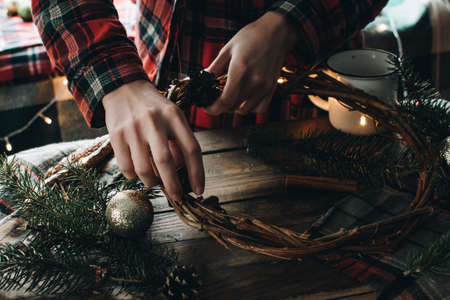 Making of Christmas wreath from nature materials on a dark wooden table. Scandinavian hygge styled Christmas composition. Cozy winter homely scene with decorations.の写真素材