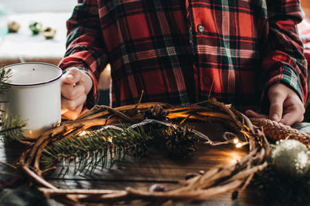 Making of Christmas wreath from nature materials on a dark wooden table. Scandinavian hygge styled Christmas composition. Cozy winter homely scene with decorations.の写真素材