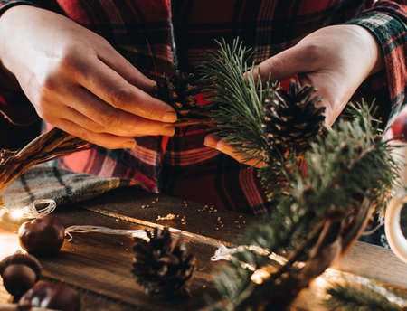 Making of Christmas wreath from nature materials on a dark wooden table. Scandinavian hygge styled Christmas composition. Cozy winter homely scene with decorations.の写真素材