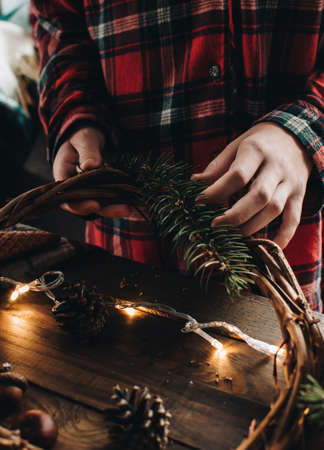 Making of Christmas wreath from nature materials on a dark wooden table. Scandinavian hygge styled Christmas composition. Cozy winter homely scene with decorations.の写真素材