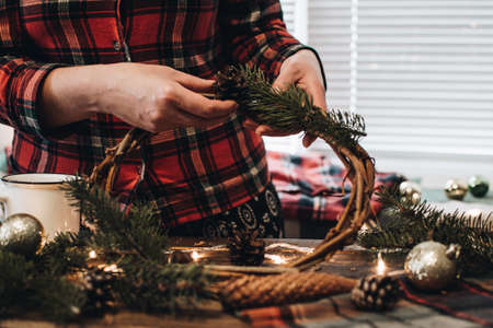 Making of Christmas wreath from nature materials on a dark wooden table. Scandinavian hygge styled Christmas composition. Cozy winter homely scene with decorations.の写真素材