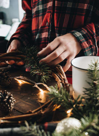 Making of Christmas wreath from nature materials on a dark wooden table. Scandinavian hygge styled Christmas composition. Cozy winter homely scene with decorations.の写真素材