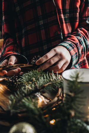 Making of Christmas wreath from nature materials on a dark wooden table. Scandinavian hygge styled Christmas composition. Cozy winter homely scene with decorations.の写真素材