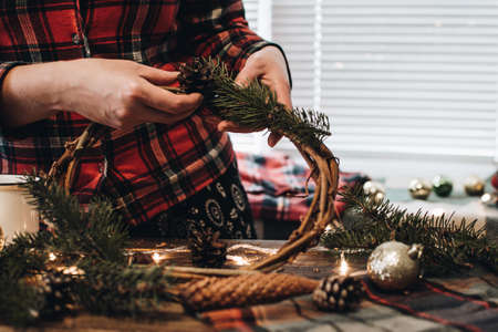 Making of Christmas wreath from nature materials on a dark wooden table. Scandinavian hygge styled Christmas composition. Cozy winter homely scene with decorations.の写真素材
