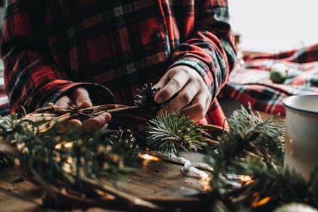 Making of Christmas wreath from nature materials on a dark wooden table. Scandinavian hygge styled Christmas composition. Cozy winter homely scene with decorations.の写真素材