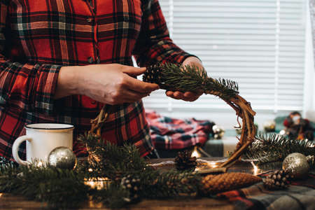Making of Christmas wreath from nature materials on a dark wooden table. Scandinavian hygge styled Christmas composition. Cozy winter homely scene with decorations.の写真素材
