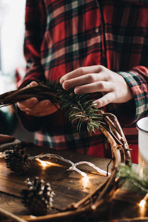 Making of Christmas wreath from nature materials on a dark wooden table. Scandinavian hygge styled Christmas composition. Cozy winter homely scene with decorations.の写真素材