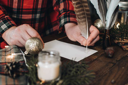 Writing of Christmas postcard for friends or letter for Santa Claus. Scandinavian hygge style Christmas composition. Cozy winter homely scene. Background with christmas decor.の写真素材