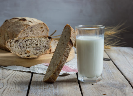 Russian wholegrain homemade wheat bread on the board  with milk in a cup on wooden table