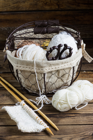 Wool yarn and knitting needles in a vintage basket on a dark wooden surface. Vintage style. Selective focus.の写真素材