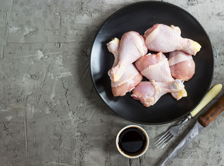 Raw chicken legs on a black dress on a concrete background. Top view. Copy spaceの写真素材