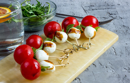Skewers with tomatoes, arugula, mozzarella balls and balsamic sauce. Selective focus.の写真素材