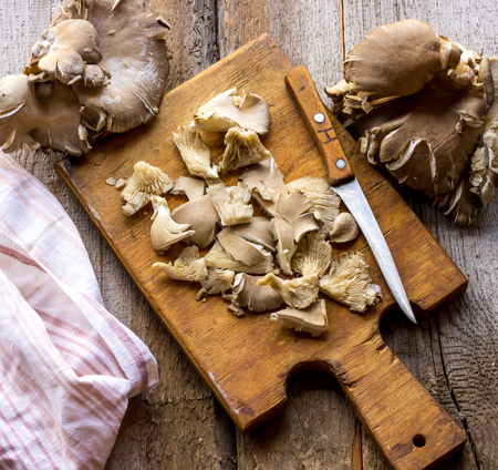 Oyster mushroom and a knife on wooden cutting board. Top viewの写真素材