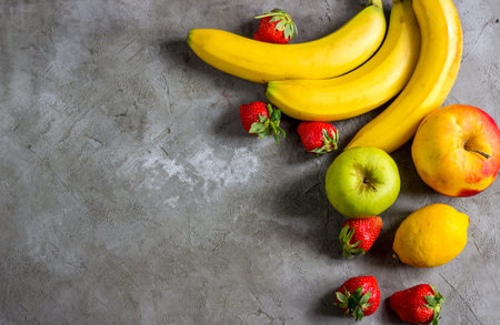 Bananas, apples, lemon and strawberries on a concrete background.  Space for text. Top viewの写真素材
