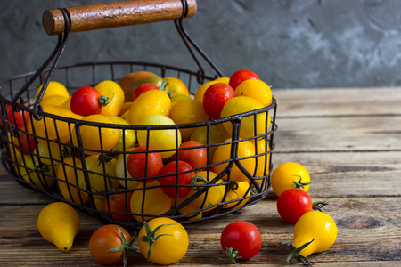 Colorful tomatoes in the basket, red tomatoes, yellow tomatoes. Tomatoes background. vintage wooden backgroundの写真素材