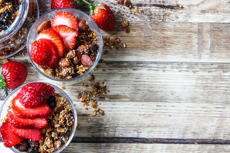 homemade yogurt with granola and strawberry in glasses on rustic wooden table. healthy breakfastの写真素材