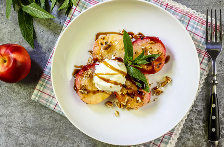 Baked peaches with ice cream on a plate on a gray metal backgroundの写真素材