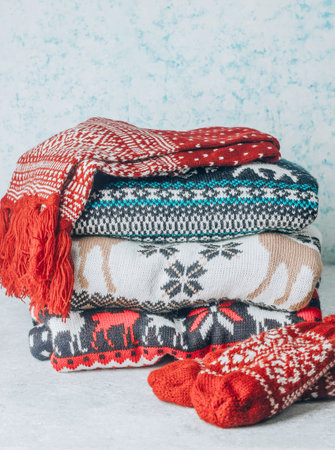 Warm woolen sweaters, scarf and mittens on grey