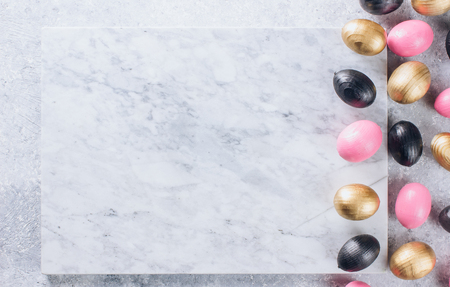 Stylish Frame background with black, pink and gold decorative wooden easter eggs with copy space for text. isolated on white marble background. Flat lay, top view. Easter conceptの写真素材