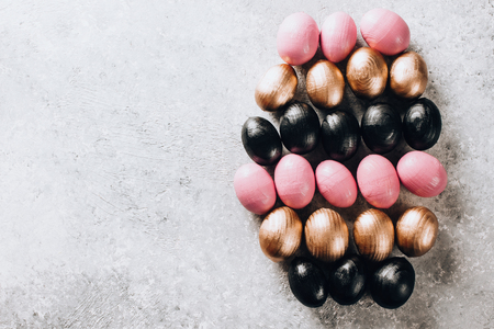 Stylish Frame background with black, pink and gold decorative wooden easter eggs with copy space for text. isolated on white marble background. Flat lay, top view. Easter conceptの写真素材